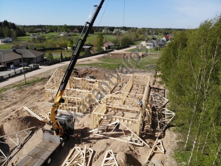 Medinių stogo santvarų montavimas statybose Stogo santvarų montavimas kranu statybvietėje
